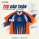 Ảnh minh họa áo đá bóng trường TIS màu navy cam, logo trường giữa ngực, bông lúa hai vai, sọc dọc thân dưới