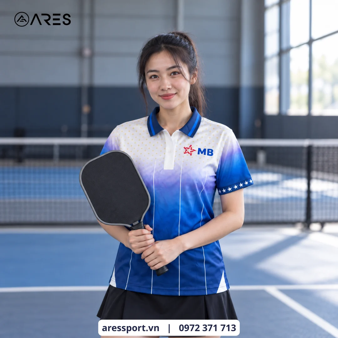 Ảnh minh họa áo lên người do AD dựng cảnh: người mẫu nữ mặc polo pickleball in logo MB ARES may bằng vải Mè Hàn Quốc, trên sân pickleball trong nhà